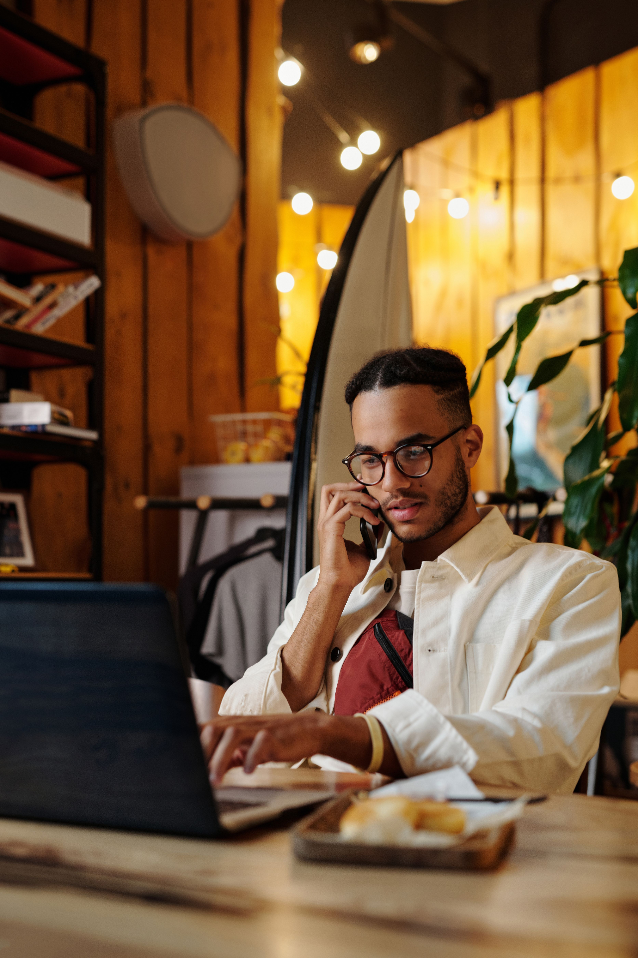 Pequeno empreendedor sorrindo usando celular e notebook no seu negócio local